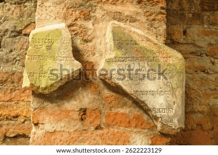Two Broken Stone Tablets with Ancient Writings Displayed on a Weathered Brick Wall. My Son, Vietnam.