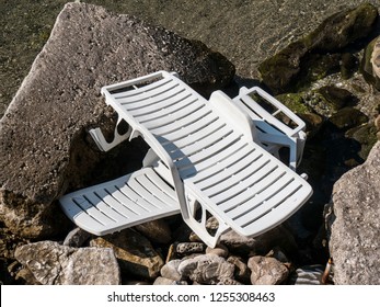 Two Broken White Plastic Sun Bed On Seaside Rocks Top View