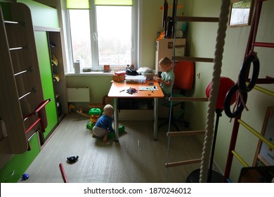 Two brothers boy, 2 and 5 years old, are playing at home in the children's room with toys. Belarus, Minsk, 2020.