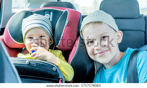 Two brothers in car smiling and\
enjoying togetherness. Two child boys looking into camera\
