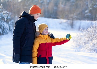 Two Brothers Doing Selfie On Nature In Winter Park. Kids Using Mobile Phone