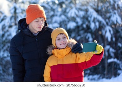 Two Brothers Doing Selfie On Nature In Winter Park. Kids Using Mobile Phone