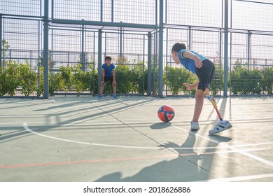 Two brothers playing football, one of them has a leg prosthesis and is kicking a penalty. Siblings playing sports together.