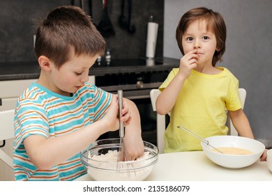 Two brothers prepare cake dough in the kitchen at home. Time with children at home. Children in the kitchen. Cooking with children. Children kneading dough