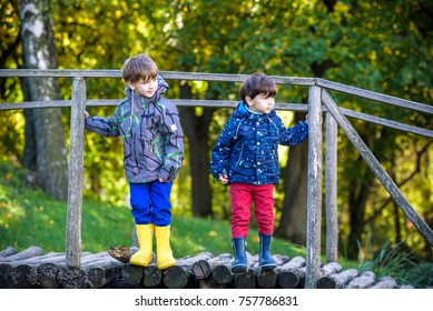 Two brothers sibling boy child crossing little wooden bridge in mountains. Dressed in warm closes. Sunny autumn day at forest park. Travel relax adventure friendship concept. - Powered by Shutterstock