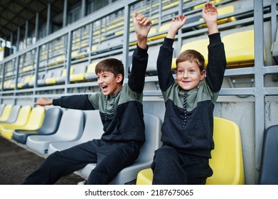 Two brothers support their favorite team, sitting on the sports podium at the stadium. - Shutterstock ID 2187675065