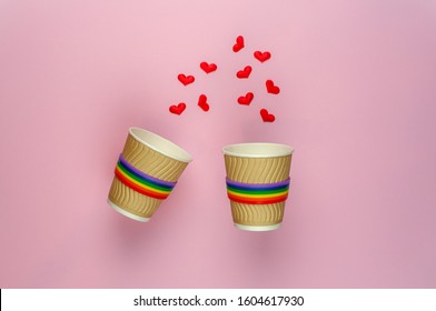 Two Brown Coffee Cups With Rainbow Ribbon Levitate Over A Pink Background With Hearts Mocap For A Photo. The Concept Of LGBT Pride. Valentine's Day