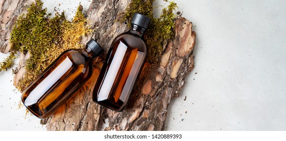 Two brown glass Mock up bottles of shampoo and conditioner of cosmetics over Natural background of real tree bark, tiny mosses and grass organic with copy space. Flat lay. banner