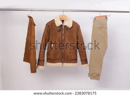 Two brown leather jacket with beige fur  with khaki pants on  hanger 