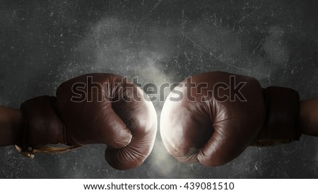 Two brown old boxing gloves hit together