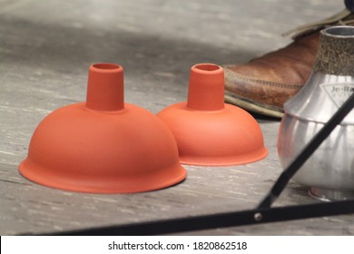 Two Brown Red Toilet Plungers And A Brass Mute For Trombones. Close Up Of Brass Instrument Gear.