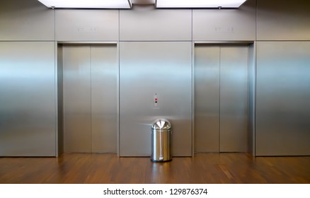 Two brushed metal elevator doors in a minimalistic style building interior
