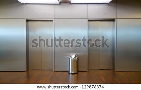 Two brushed metal elevator doors in a minimalistic style building interior