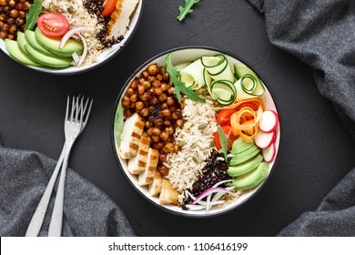 Two buddha bowl. Clean and balanced healthy food concept. Chicken grilled steak, rice, spicy chickpeas, black and white quinoa, avocado, carrot, zucchini, radish, tomatoes on dark background, top view