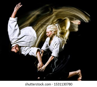 two budokas fighters man and woman practicing Aikido studio shot isolated on black background