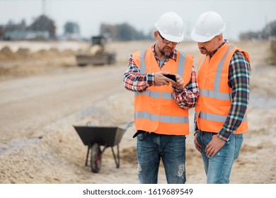 Two builders checking road construction plan on the phone - Powered by Shutterstock