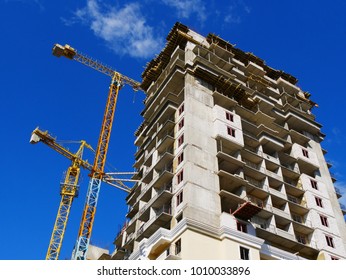 two building cranes on the background of a high-rise multi-storey building under construction. construction site.