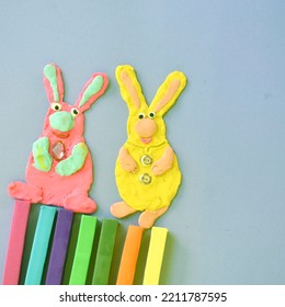 Two Bunnies Made Of Plasticine On A Gray Background