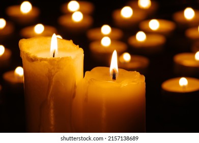 Two burning candles in the dark against the background of blurry lights