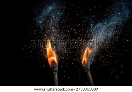 Two burning matches exploding with sparks against a black background