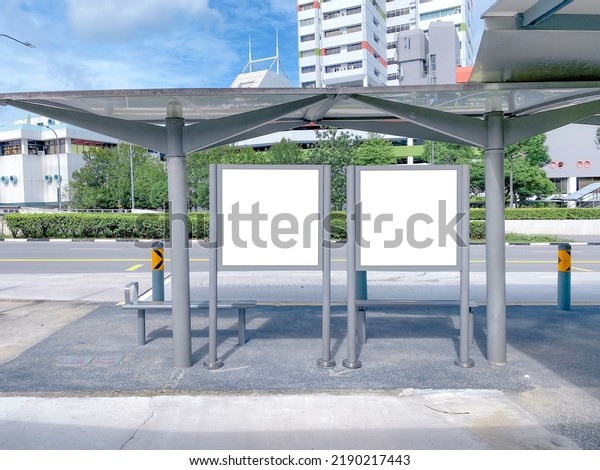 Two bus stop blank advertising mock ups\
at empty bus stop shelter by main road. Out-of-home OOH classifieds\
billboard advertisement media in the\
city