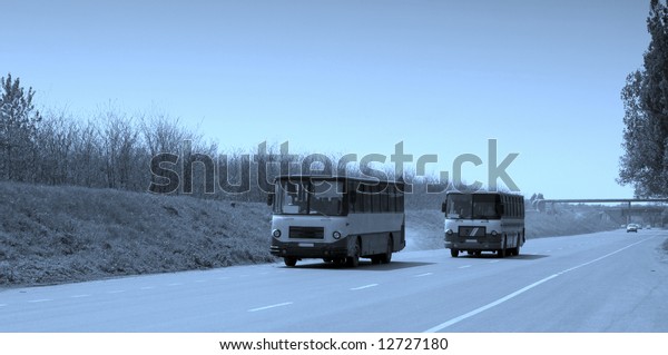 Two buses on\
the highway viewed from the\
front.