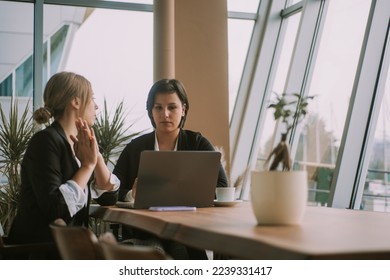 Two busines women talking and looking at the laptop while sitting at the office