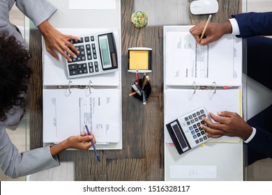 Two Business Colleagues Calculating Tax In Office