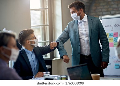 Two Business Colleagues Greeting With Elbows While Wearing Protective Face Mask On A Meeting During Coronavirus Pandemic. 