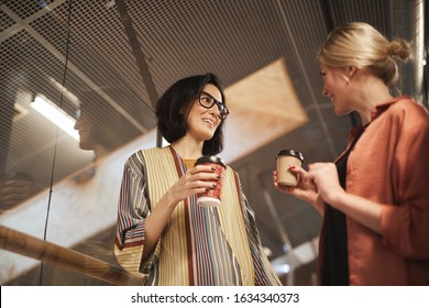 Two Business Colleagues Holding Cups Of Coffee And Talking To Each Other While Meeting At Office Corridor