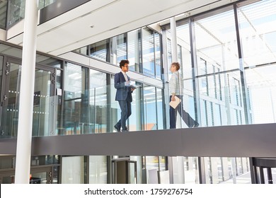 Two Business Colleagues Walk Through A Gallery In The Modern Corporate Headquarters