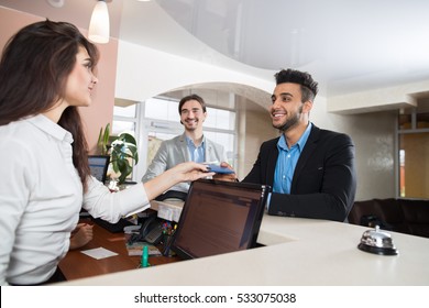 Two Business Man Arriving To Hotel Give Meeting Woman Receptionist Credit Card Pay Room Registration At Reception Counter Checking In