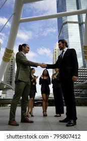 Two business man with formal suit handshake with team and city background. Businessman with agreement for working together for business project. Business handshake and business people concept. 