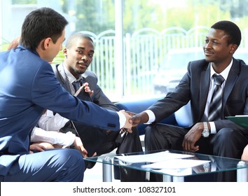 Two business man shaking hands with his team in office