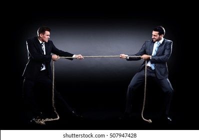 Two business men pulling rope in a competition, isolated on white background