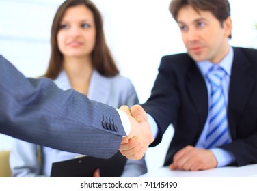 Two Business men shaking hands while team smiling at office - Powered by Shutterstock