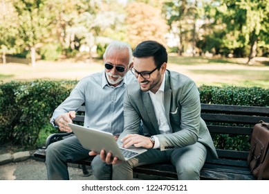 Two Business Men Using Laptop Outdoors. 