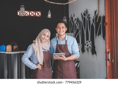 two business partner using tablet in front of their coffee shop. muslim entrepreneur concept