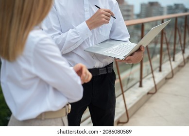 Two Business Partners Discuss Their Work And Using Laptop On The Terrace Above The City