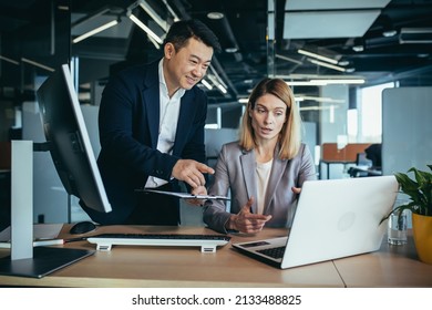 two business people consulting on a project looking at computer monitor screen sitting in the office. Asian male employee Coworker explains colleagues ideas and strategies accountant, financial report - Shutterstock ID 2133488825