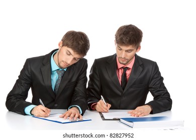 Two Business People In Elegant Suits Sitting At Desk Working In Team Together, Working With Documents Sign Up Contract, On Clipboard, Folder With Papers, Business Plan. Isolated Over White Background.