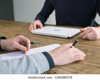 Two business people have meeting round a wooden table at an office. - Shutterstock ID 1345080578