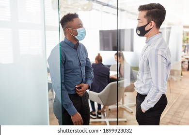 Two business people keep their distance in the office and wear mouth and nose protection - Shutterstock ID 1899923032