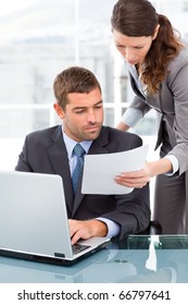 Two Business People Looking At A Paper While Working On The Laptop In The Office