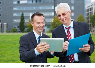 Two Business People Outside Looking At A Tablet Computer