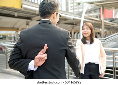 Two business people shaking hand making a deal but Business man holding crossed fingers behind back while Business woman smiling, Betray concept. - Powered by Shutterstock