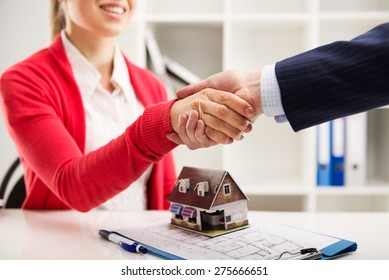 Two business people shaking hands as successful agreement in real estate agency office. Concept of housing purchase and insurance. 