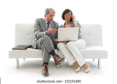 Two Business People Sitting And Working Together On A White Sofa 