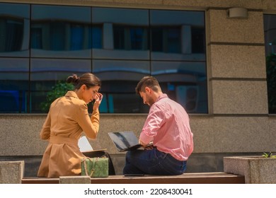 Two Business People Are Sitting And Working Outside In The City, Happy, On A Beautiful Sunny Day