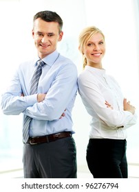 Two Business People Standing Back To Back And Smiling At Camera